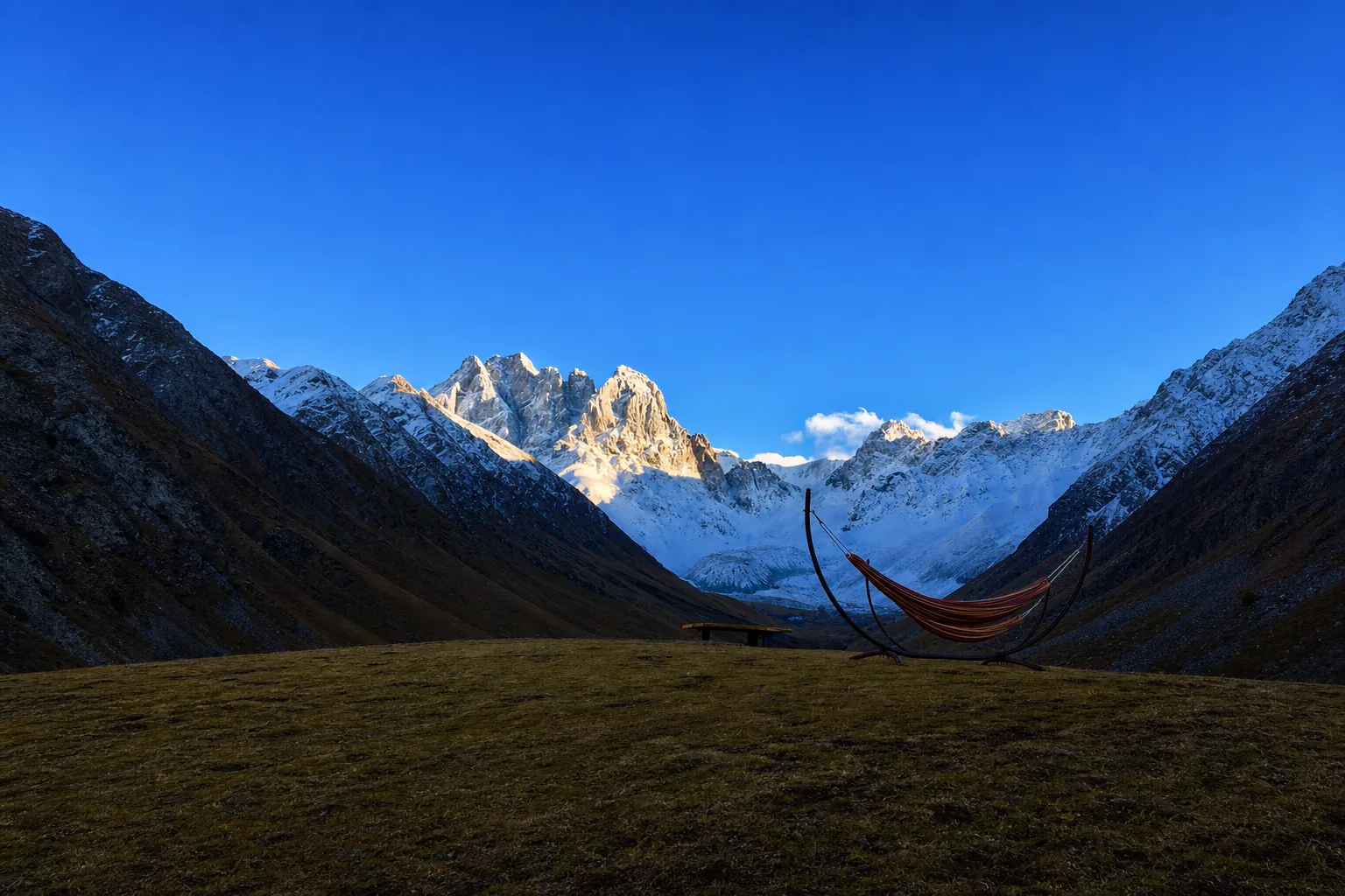 Golden evening light on a Caucasus peak above a dark valley