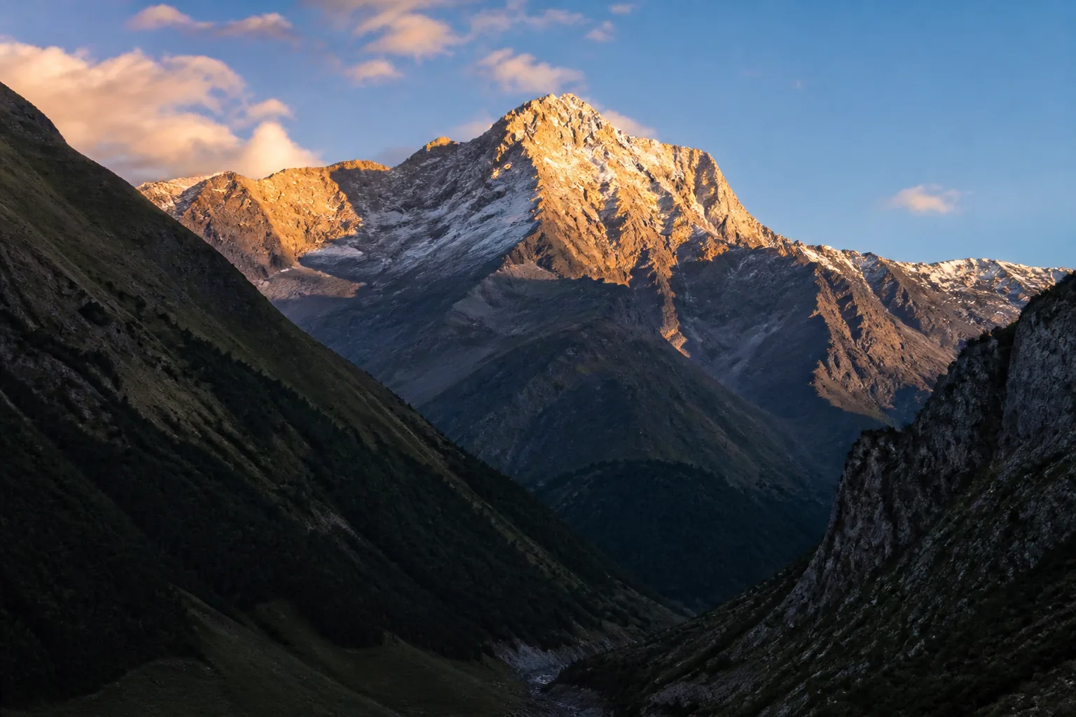Golden evening light on a Caucasus peak above a dark valley