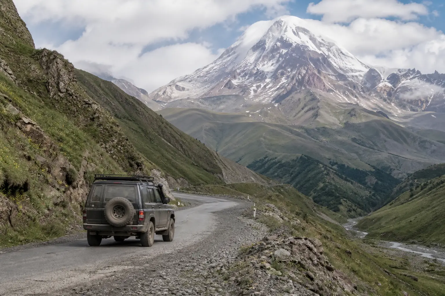 Tour 4x4 driving toward snow-capped Mount Kazbek
