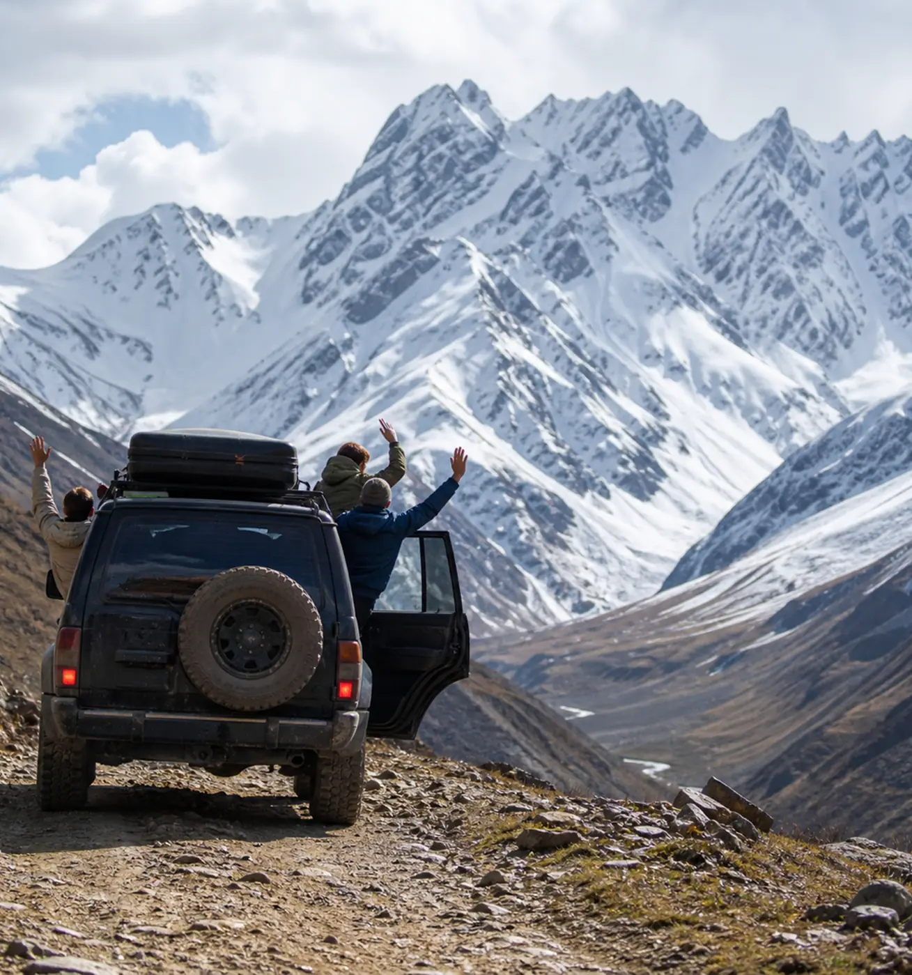 Travellers waving from a tour 4x4 below snowy Caucasus peaks